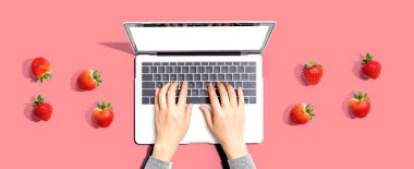 Taze çilekli dizüstü bilgisayar kullanan bir kadın.