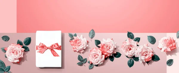 Ajándék doboz rózsaszín rózsákkal a fejünk felett — Stock Fotó