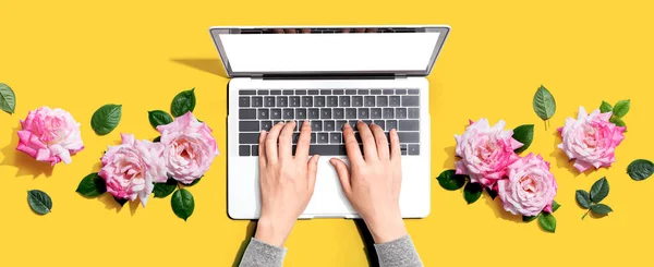 Femme utilisant son ordinateur portable avec des roses roses — Photo
