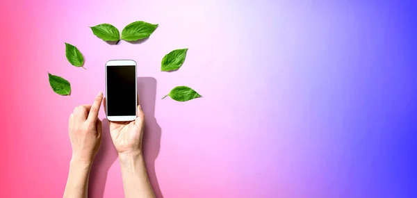 Osoba trzymająca smartfona z zielonymi liśćmi — Zdjęcie stockowe