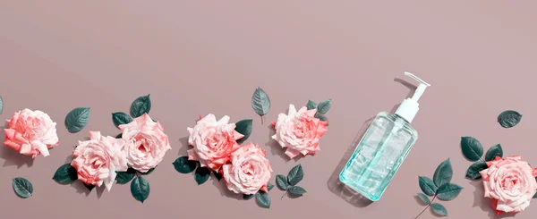 Bottiglia igienizzante con rose rosa vista aerea — Foto Stock