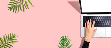 Tropikal yaprakları olan bir dizüstü bilgisayar kullanan kişi