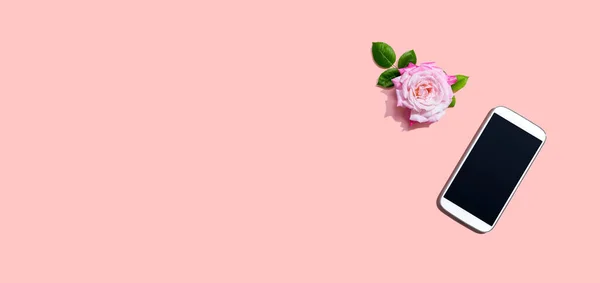 Okostelefon rózsaszín rózsával — Stock Fotó