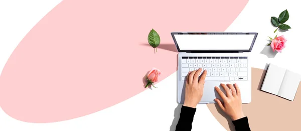 Γυναίκα χρησιμοποιεί το laptop της με ροζ τριαντάφυλλα — Φωτογραφία Αρχείου
