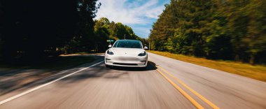 Yeni bir Tesla Model 3 tamamen elektrikli araba yolda ilerliyor.