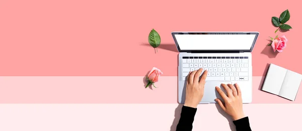 Женщина использует свой ноутбук с розовыми розами — стоковое фото