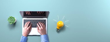 Fikir ampulü olan bir dizüstü bilgisayar kullanan kişi