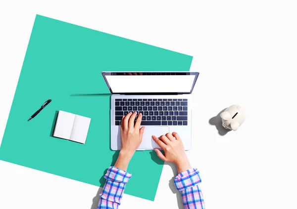 Woman using a laptop computer with a piggy bank — Stock Photo, Image