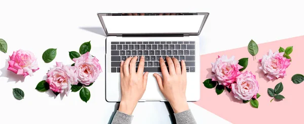Γυναίκα χρησιμοποιεί το laptop της με ροζ τριαντάφυλλα — Φωτογραφία Αρχείου