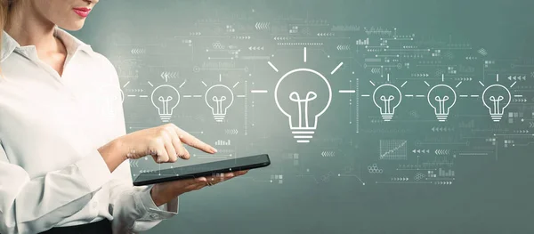 Idea light bulb theme with business woman using a tablet — Zdjęcie stockowe