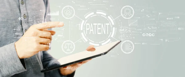Patent concept with young man holding a tablet — Stockfoto