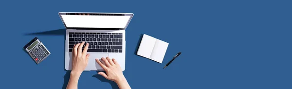 Pessoa que utiliza um computador portátil com um caderno — Fotografia de Stock