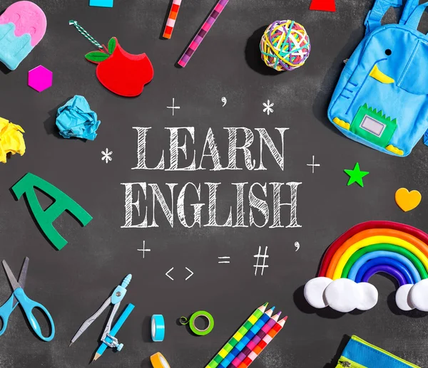 Learn English theme with school supplies on a chalkboard - flat lay