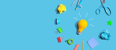 Idea light bulb with school supplies overhead view - flat lay