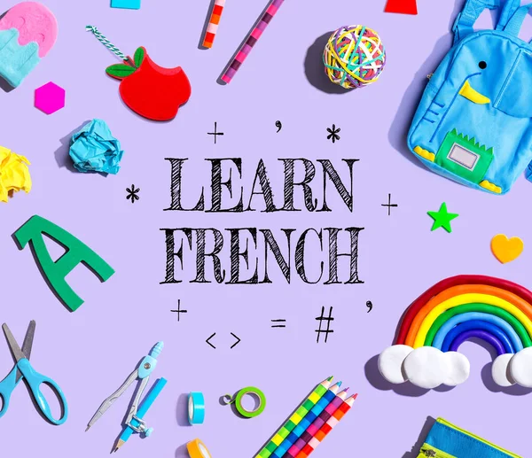 Learn French theme with school supplies on a purple background - flat lay