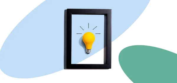 Yellow light bulb inside a frame - inspiration, creativity, energy, electricity themes