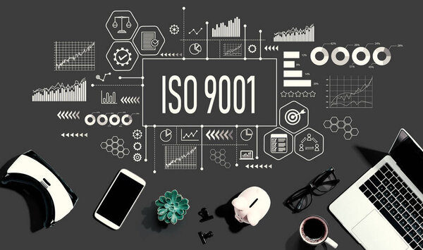 ISO 9001 theme with electronic gadgets and office supplies - flat lay