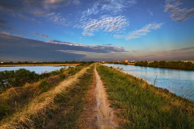 Comacchio, Emilia Romagna, Ferrara, Italy: landscape at sunset of the swamp with the path that crosses the lagoon Valli di Comacchio in the nature reserve Po Delta Park