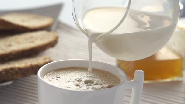 Caída de leche en cámara lenta salpicaduras en el café — Vídeo de stock