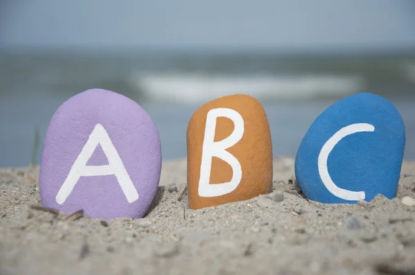 ABC op kleurrijke stenen letters op het zand — Stockfoto