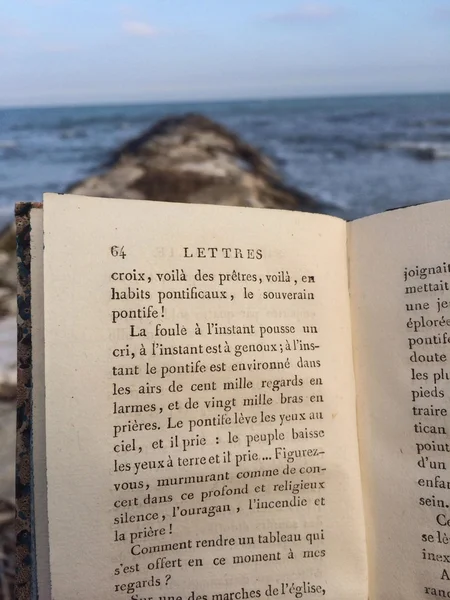 Χαλαρώσετε κατά τη διάρκεια μια ημέρα του χειμώνα στα βράχια με ένα παλιό γαλλικό βιβλίο — Φωτογραφία Αρχείου