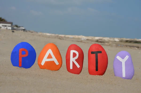 Parteiwort auf farbigen Steinbuchstaben über dem Sand — Stockfoto