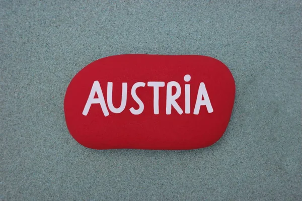 Austria, country name hand colored on a red stone over green sand