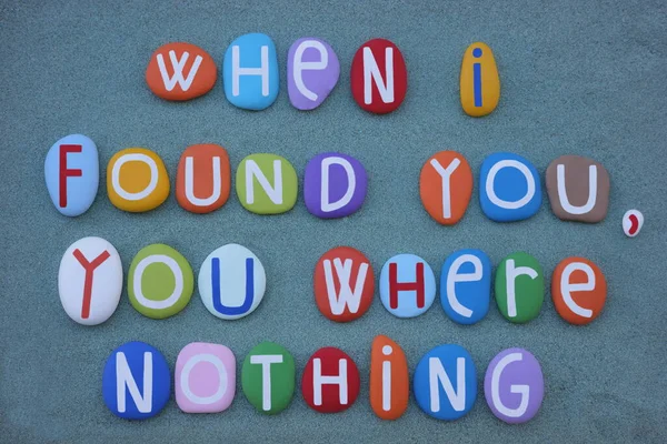 When I found you, you where nothing, creative phrase composed with multi colored stone letters over green sand