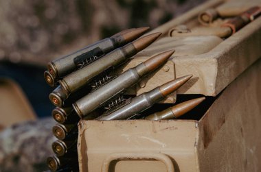 Üzerinde makineli tüfek mermisi kemeri olan metal bir cephane kutusu. Yakından birkaç kurşun görünüyor.