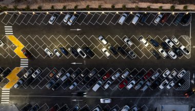 Geceleri arabalı otoparkların insansız hava görüntüsü. Kalabalık alışveriş merkezi otoparkı.