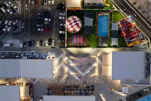 Drone vista aerea di parcheggi con auto e parco divertimenti di notte. Luminoso centro commerciale affollato — Foto Stock