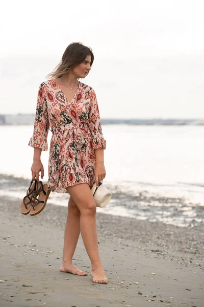 Женщина ходит босиком по песчаному пляжу. Туристическая девушка на пляже летом — стоковое фото