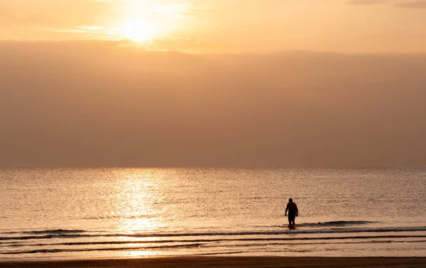 Silhuett av en man i havet vid soluppgången. Okänd person som simmar i havet på morgonen. — Stockfoto