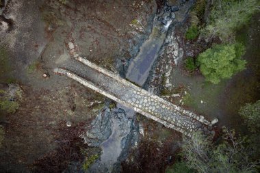 Nehirde su akan bir ortaçağ taşlı köprüsünün insansız hava aracı manzarası. Elia Köprüsü Troodos Kıbrıs