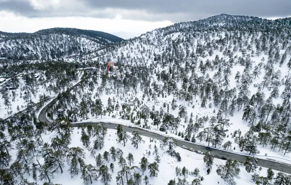 Drone aerial photograph of an asphalt motorway crossing the snowy mountain in winter. — Stockfoto