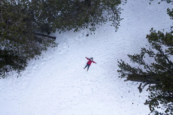 Drone aerial of woman wearing warm clothing lie down at snow in winter. Troodos cyprus — Stockfoto