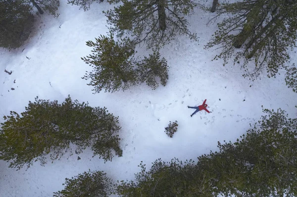 Drone aerial of woman wearing warm clothing lie down at snow in winter. Troodos cyprus — Stockfoto