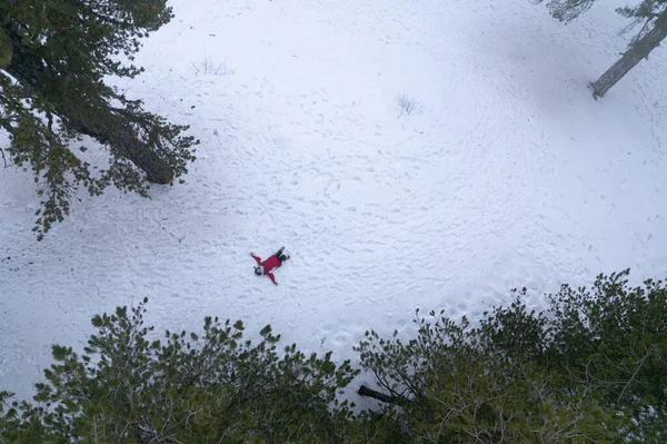 暖かい服を着た女性のドローン航空機は冬に雪の上に横たわっています。トロイの木馬｜cyprus — ストック写真