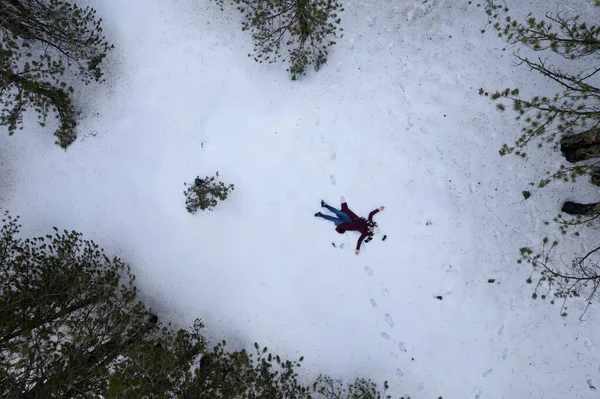 Drone aerial of woman wearing warm clothing lie down at snow in winter. Troodos cyprus — ストック写真