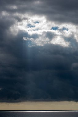 Gün batımında denizin üstünde dramatik gökyüzü olan fırtınalı bulutlar.