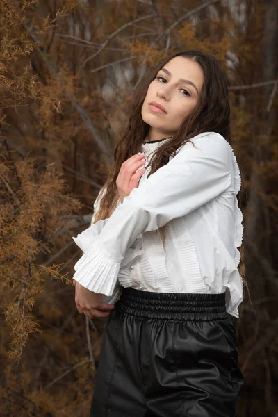 Portrait tête d'affiche d'une jeune femme aux cheveux longs portant une robe noire et blanche posant à l'extérieur. — Photo