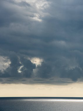 Gün batımında denizin üstünde dramatik gökyüzü olan fırtınalı bulutlar.