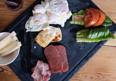 Tabakta geleneksel İngiliz kahvaltısı. Fırında yumurta, halloumi, peynirli jambon ve sebze..