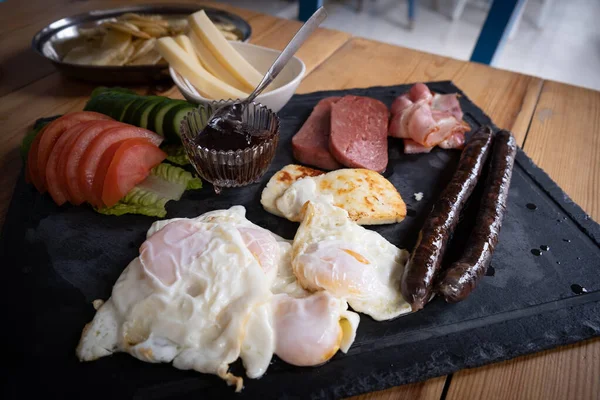 Traditionell engelsk frukost på tallrik. Bakade ägg, halloumi, ostskinka och grönsaker. — Stockfoto