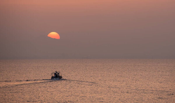 Рыбацкая лодка, плывущая по морю, чтобы поймать рыбу на закате