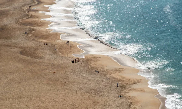 Twee mensen lopen alleen op een zandstrand. Nazare Portugal — Stockfoto