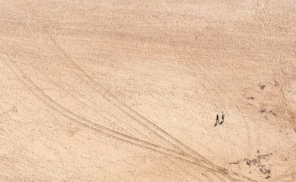 Dwoje ludzi spacerujących samotnie po piaszczystej tropikalnej plaży. Nazare Portugalia — Zdjęcie stockowe