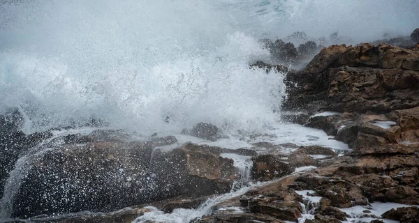 Stürmische, windige Wellen krachen an einer felsigen Küste auf die Felsen — Stockfoto