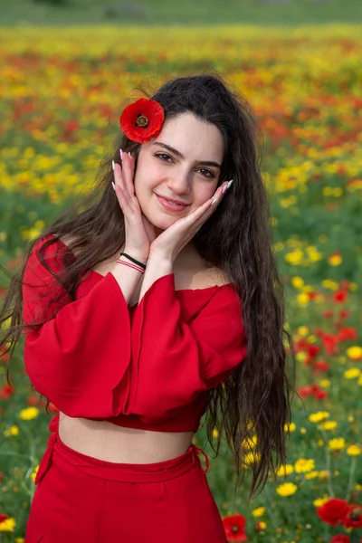 Portrait of a young woman dressed in red smiling in the field in spring. — ストック写真