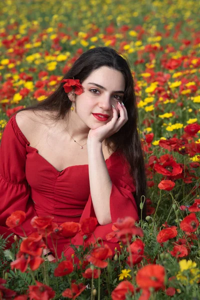 Portrait of a young woman dressed in red smiling in the field in spring. — ストック写真